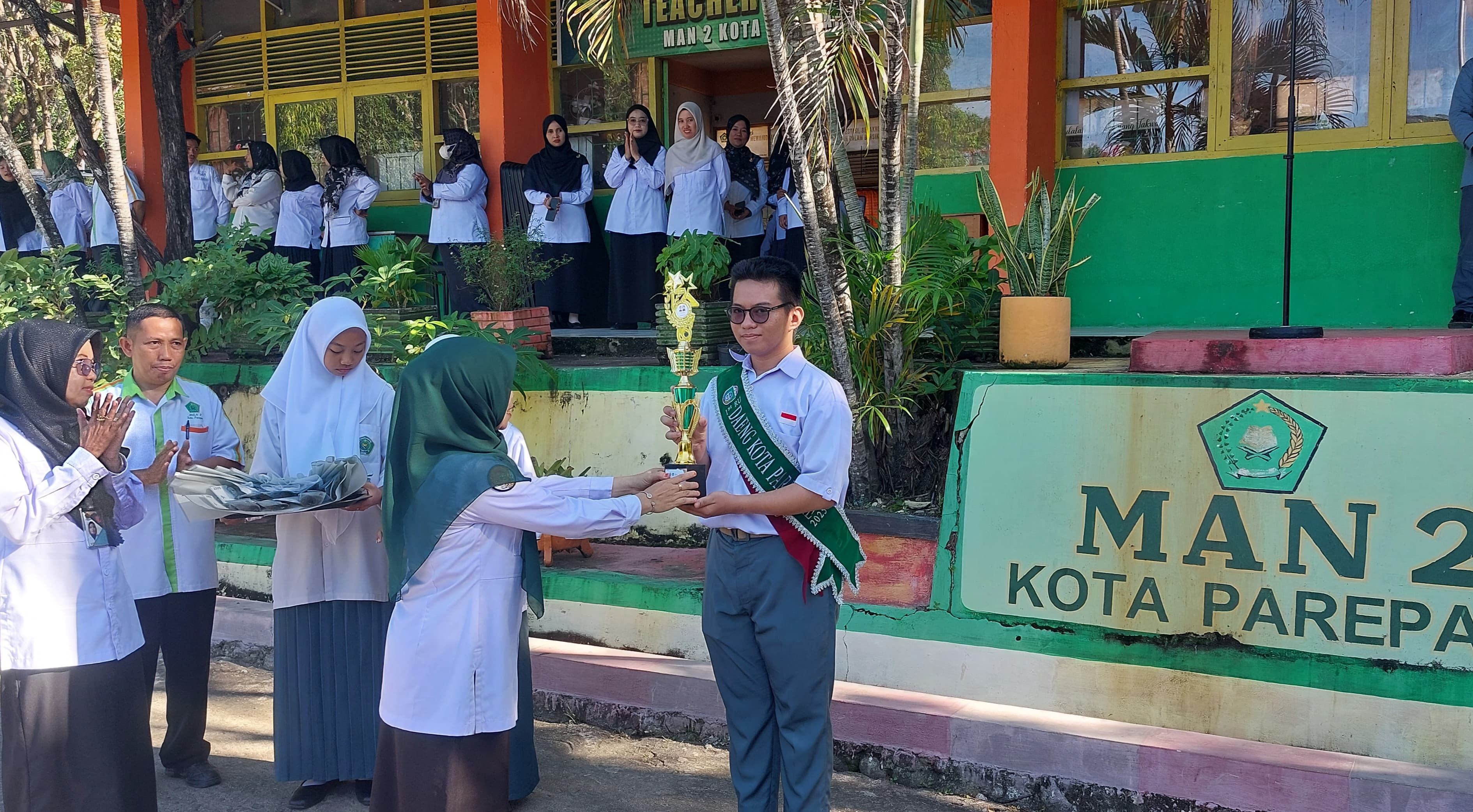 Plh. Kepala MAN 2 Kota Parepare memasangkan selempang sekaligus menyerahkan trofi, sertifikat, dan hadiah