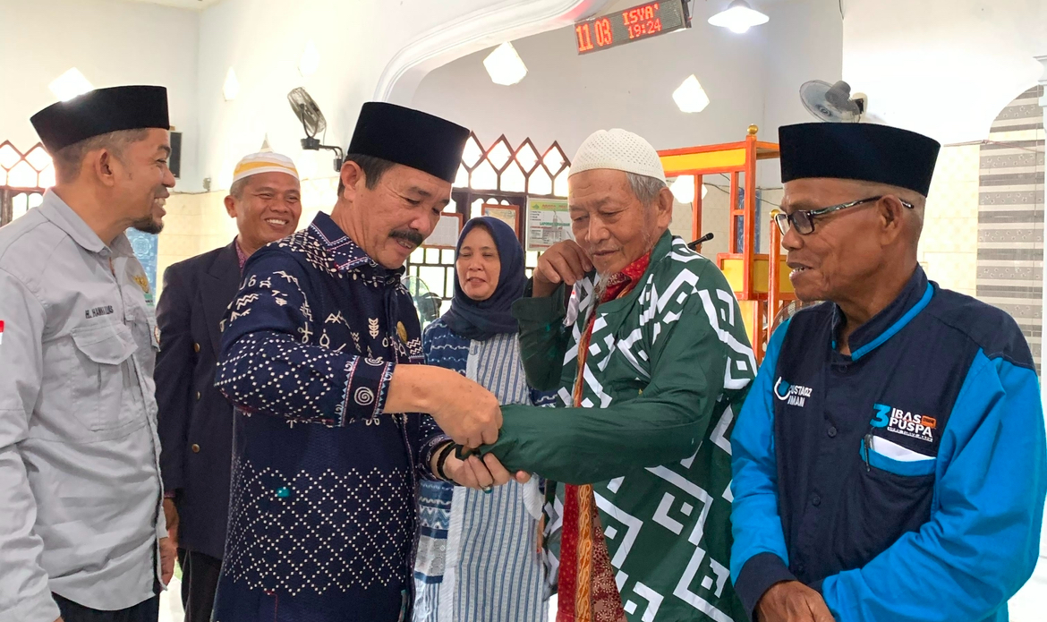 HM. Yunus saat memasangkan busana muslim kepada imam Masjid